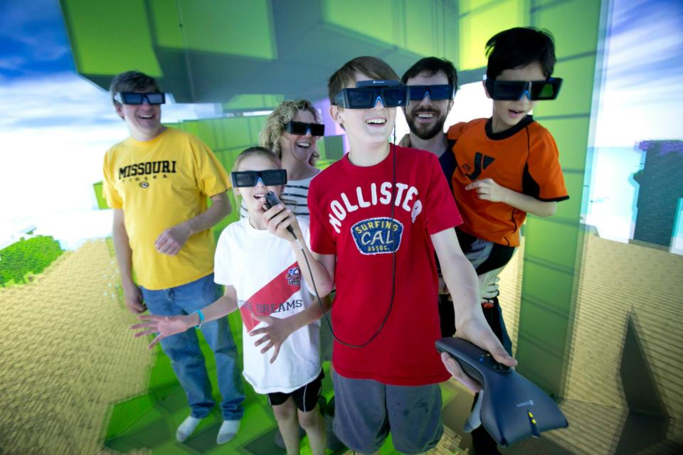 A group of Open House visitors explores the six-sided 3D immersive virtual environment of Duke's DiVE.